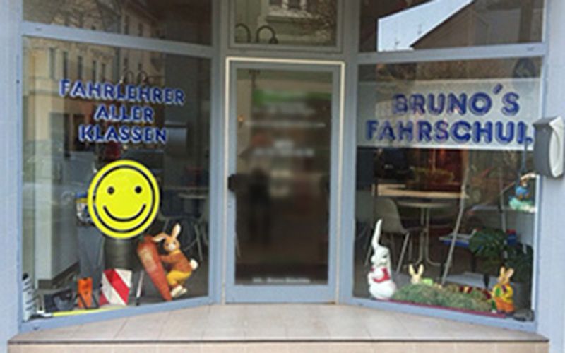 Eingang der Filiale in Bochum-Langendreer, auf der Scheibe „Fahrlehrer aller Klassen“ und ein gelber Smiley